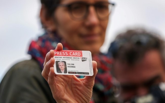 Uma manifestante mostra um cartão de imprensa da Associação Croata de Jornalistas com o nome de Julian Assange, em Zagreb, em 20 de fevereiro de 2024, durante um comício em apoio ao fundador do WikiLeaks