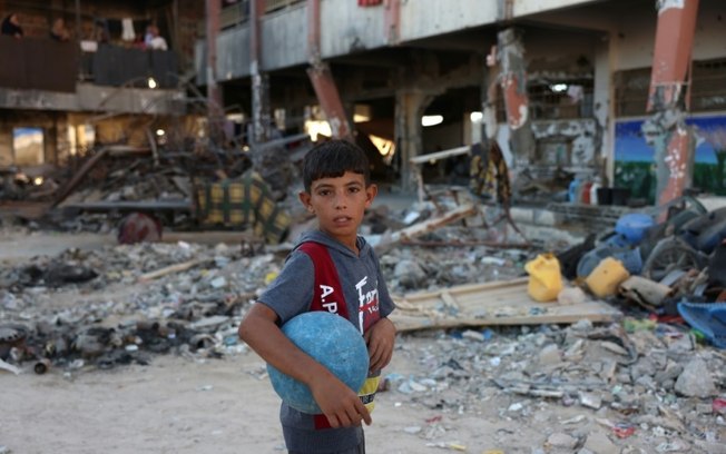 Um menino caminha em uma escola destruída por ataques israelenses em Khan Yunis, no sul da Faixa de Gaza, em 17 de setembro de 2024