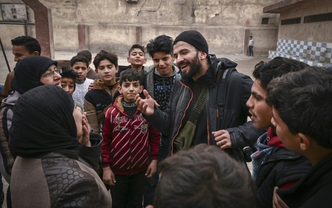 O fotógrafo sírio da AFP Sameer al-Doumy encontra seus vizinhos após voltar para sua antiga escola em Douma, perto de Damasco