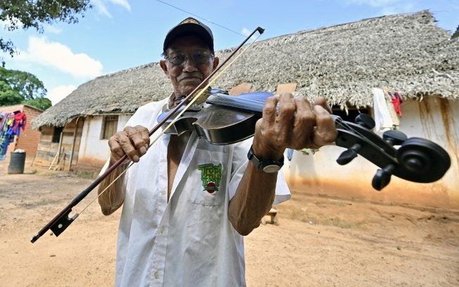 Hildeberto Oreyai toca violino do lado de fora de sua casa em Urubichá, Bolívia, em 22 de abril de 2024