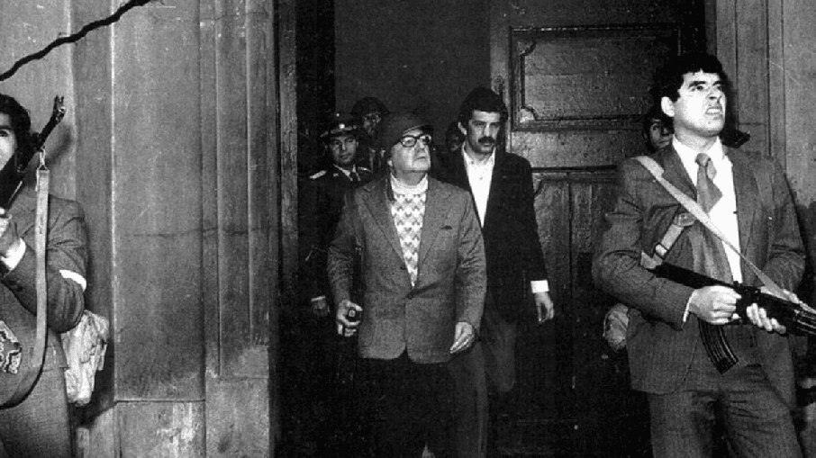 Salvador Allende, de capacete e armado, saindo do palácio