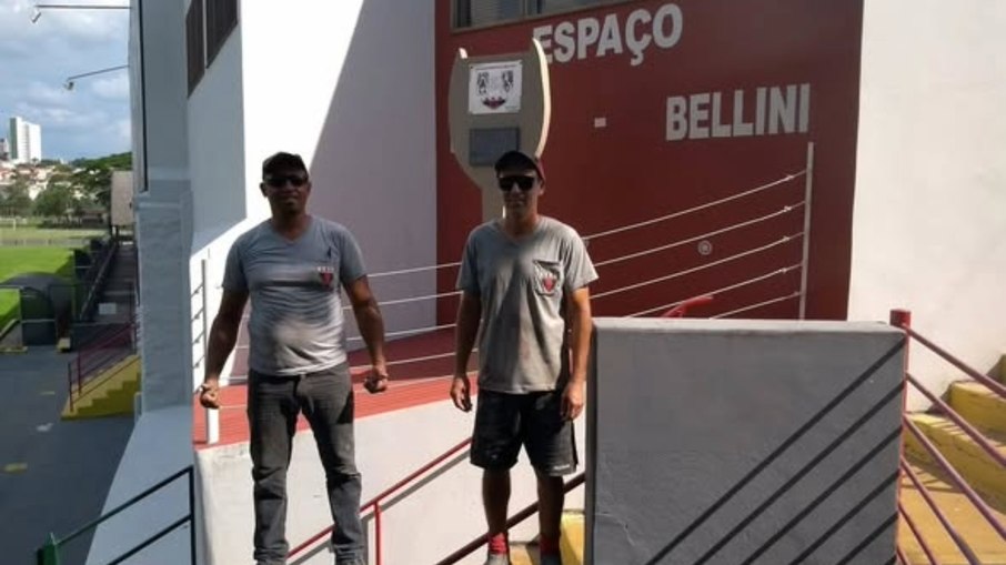 Funcionários Alexandre e Lucinho, na manutenção do espaço que homenageia Mauro e Bellini, com uma alusão à Taça Jules Rimet