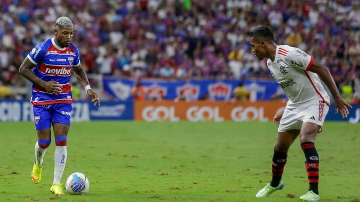 Patrocínio Novibet no Fortaleza: Marinho conduz a bola diante de Alex Sandro do Flamengo em partida disputada em 2024