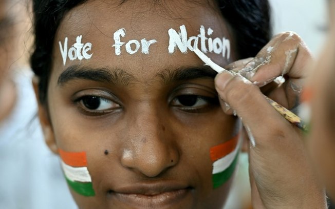 Aluna de escola de arte pinta o rosto e convoca a população a votar, em Mumbai