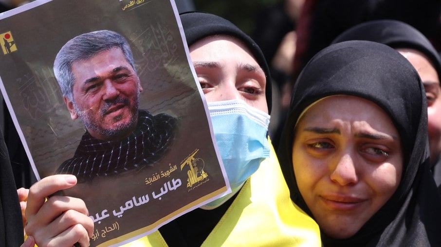 Mulheres enlutadas reagem enquanto seguram o retrato de Taleb Abdallah, conhecido como Abu Taleb, comandante sênior do Hezbollah morto em ataque israelense