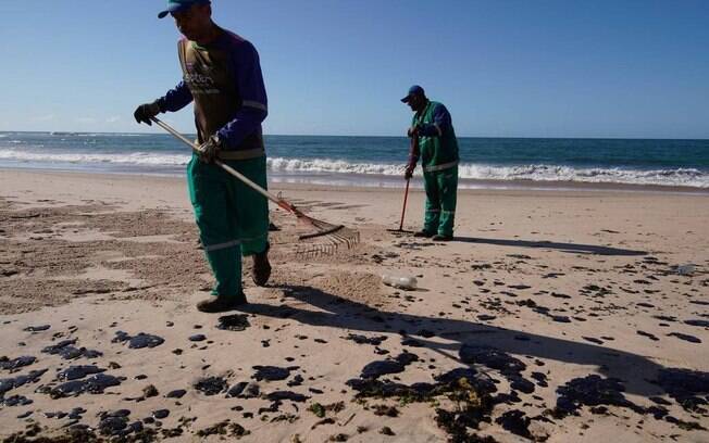 Agentes limpam óleo na Praia da Pituba, em Salvador