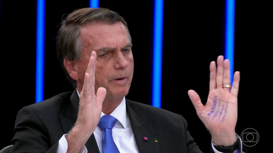 Bolsonaro mostra a mão com cola durante o Jornal Nacional