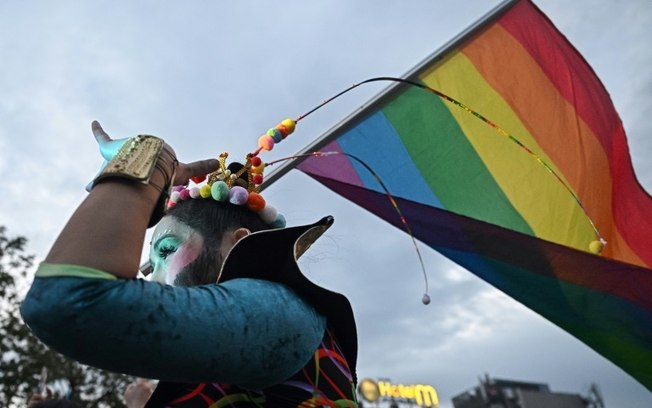 Um membro da comunidade LGBTQIA  agita uma bandeira do arco-íris durante uma parada do orgulho gay em 26 de maio de 2024 em Chiang Mai, norte da Tailândia