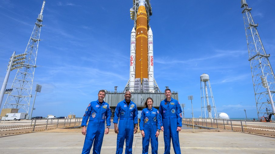 Os astronautas da NASA Reid Wiseman, comandante do Artemis II, à esquerda, Victor Glover, piloto do Artemis II, Christina Koch, especialista da missão Artemis II, e o astronauta da CSA (Agência Espacial Canadense) Jeremy Hansen, especialista da missão Artemis II, à direita, param para uma fotografia de grupo enquanto visitam o foguete Artemis II SLS (Sistema de Lançamento Espacial) da NASA e a espaçonave Orion, segunda-feira, 30 de março de 2026, no Complexo de Lançamento 39B do Centro Espacial Kennedy da NASA, na Flórida