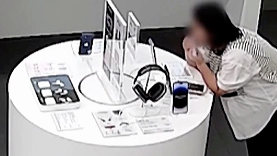 Mulher foi flagrada por câmeras de uma loja na China roendo o cabo de segurança que prendia um iPhone 14 Plus ao balcão