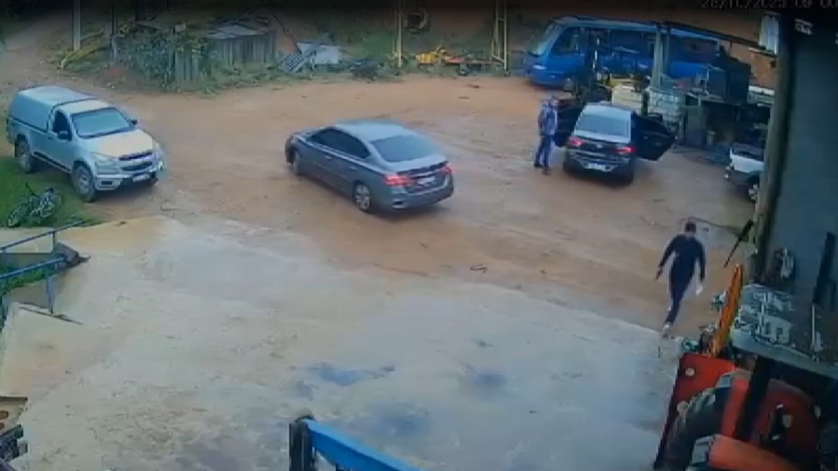 Suspeito caminha com papel na mão para abordar a vítima Suspeito caminha com papel na mão para abordar a vítima