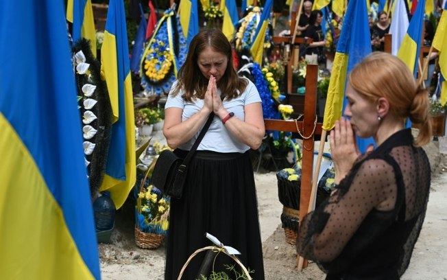 Duas mulheres visitam o cemitério militar de Lychakiv, na cidade ucraniana de Lviv, em 22 de junho de 2024, Dia do Luto e da Recordação pelas Vítimas da Guerra