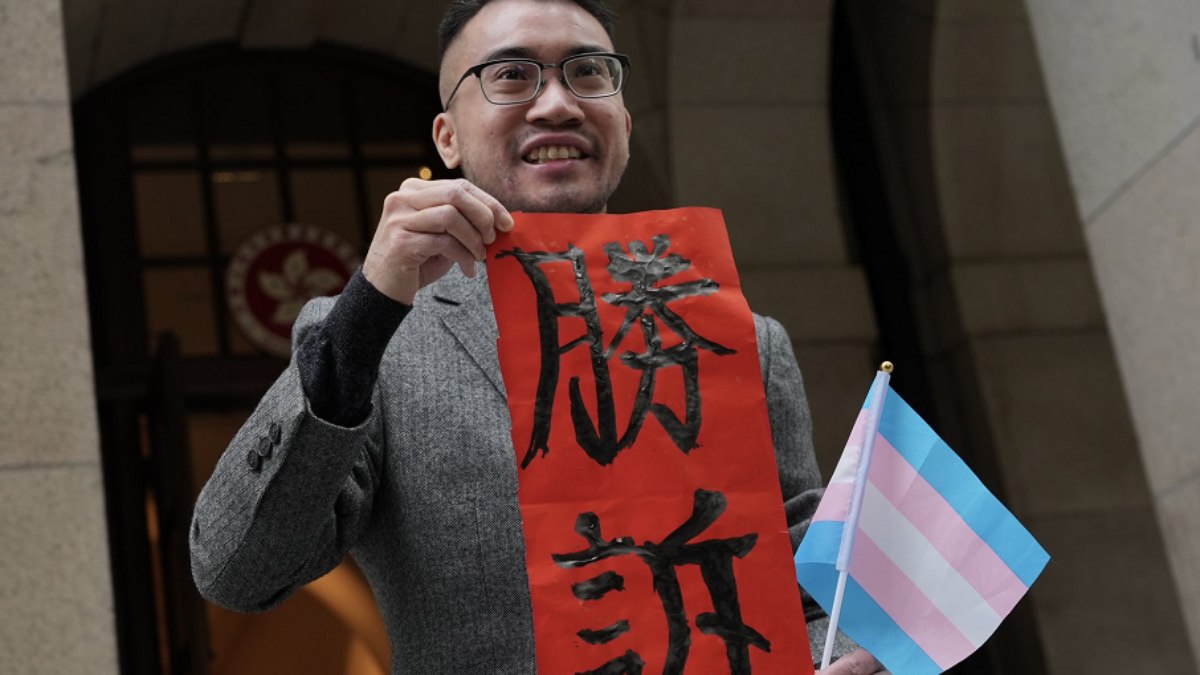 O ativista trans japonês Henry Tse posa com uma faixa escrita 'vitória legal' fora do Tribunal de Última Instância de Hong Kong.