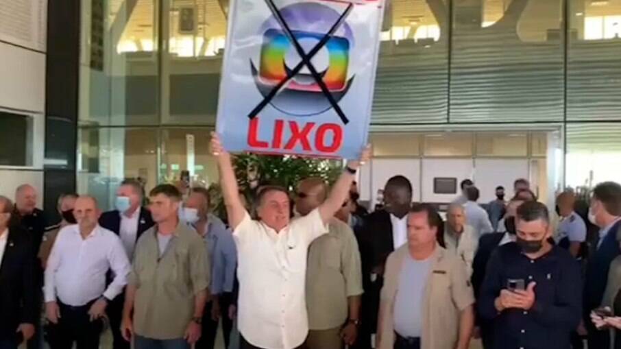 Bolsonaro compareceu sem máscara a aeroporto no Paraná e levantou cartaz com xingamentos à Globo