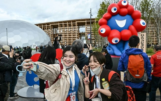 Visitantes posam com o mascote da Exposição Universal de Osaka no dia de abertura ao público, em 13 de abril de 2025