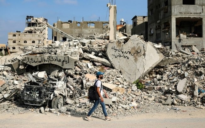 Homem caminha ao lado de escombros após bombardeios israelenses no campo de Al Bureij, centro de Faixa de Gaza, em 3 de junho de 2024