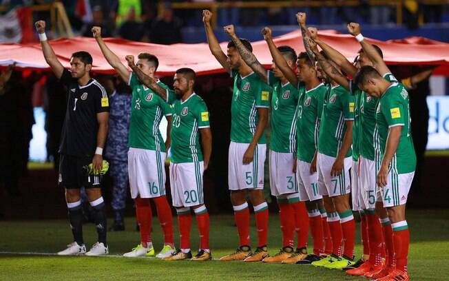 Jogadores mexicanos respeitam um minuto de silêncio com os punhos levantados em homenagem às vítimas do terremoto