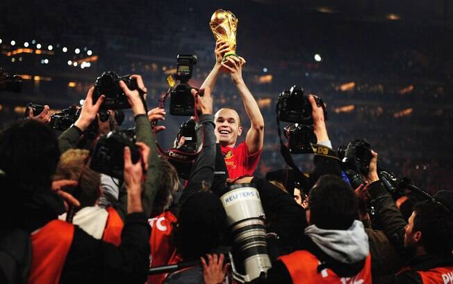Cercado de fotógrafos, Andrés Iniesta levanta a taça da Copa do Mundo depois da final contra a Holanda