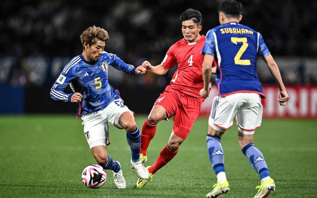 Kim Pom Hyok  (da Coreia do Norte, de vermelho) disputa a bola com o japonês Morita durante o duelo desta quinta-feira, pelas Eliminatórias asiáticas, em Tóquio