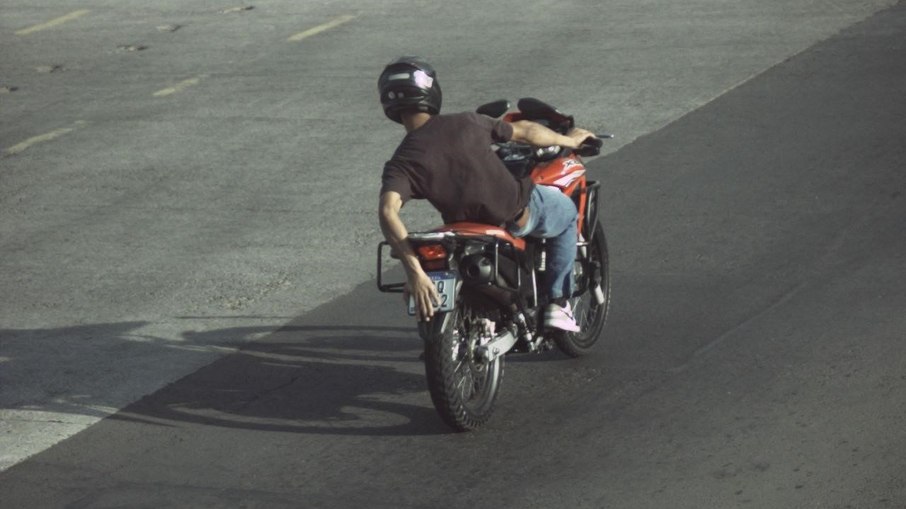Motorista tenta esconder a placa e se coloca em desequilíbrio