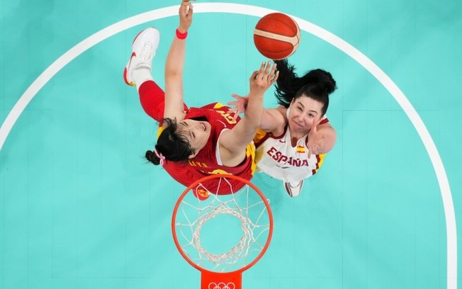 Plano central mostra a espanhola Megan Gustafson (à direita) disputando um rebote na partida de basquete do grupo A nos Jogos Olímpicos de Paris, no estádio Pierre-Mauroy em Villeneuve-d'Ascq, no dia 28 de julho de 2024