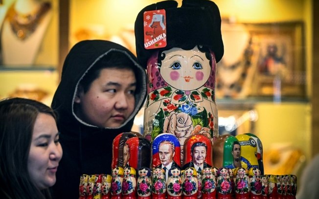 Turistas olham para bonecas russas com retratos do presidente chinês Xi Jinping e do presidente russo Vladimir Putin em 15 de novembro de 2023 em Moscou