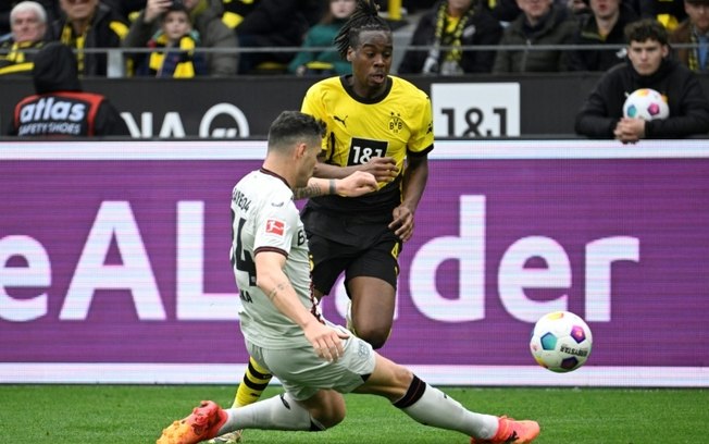 O volante suíço do Bayer Leverkusen,  Granit Xhaka, intercepta o avanço do inglês do Borussia Dortmund Jamie Bynoe-Gittens