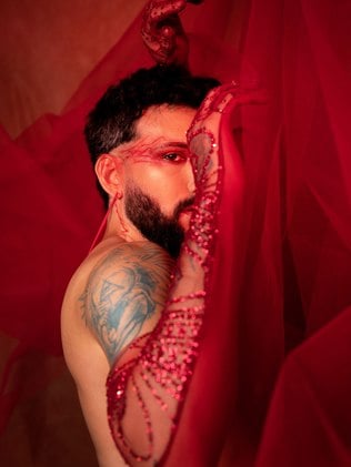 Juan Guiã em um fundo, roupas e maquiagem vermelha 