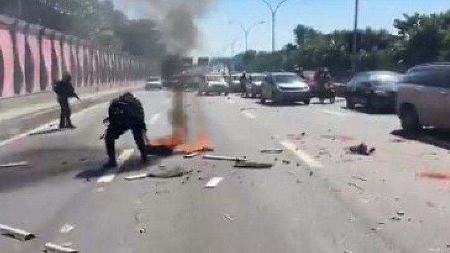 Policial Militar retirando um dos artefatos colocados para bloquear a pista Policial Militar retirando um dos artefatos colocados para bloquear a pista