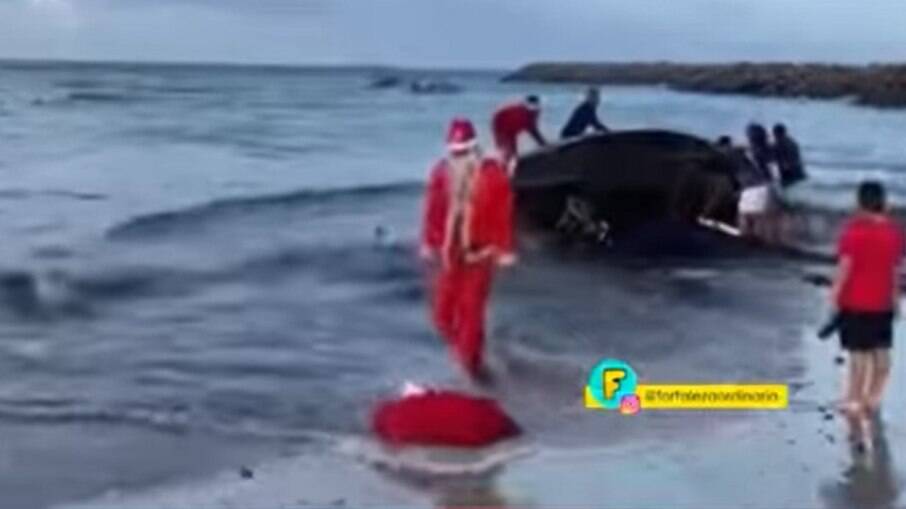 Papai Noel cai na água após chegar de jangada em praia no Ceará