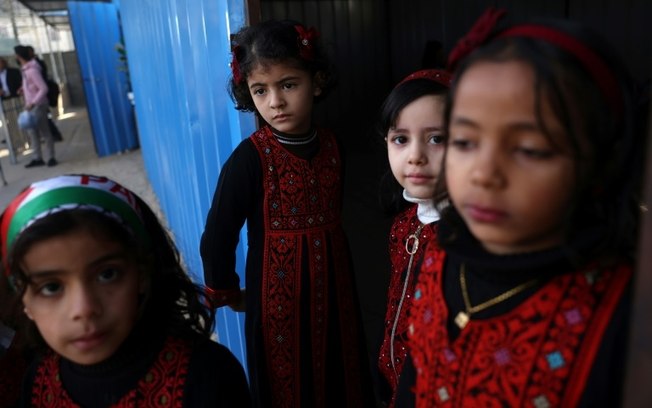 Meninas palestinas com roupas tradicionais participam da inauguração da “Life USA School”, em Khan Yunis, afiliada ao Ministério da Educação palestino e financiada pela Life For Relief and Development Foundation, em 11 de dezembro de 2024