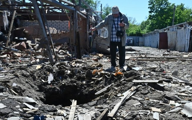Um morador da cidade ucraniana de Kharkiv inspeciona uma cratera perto de garagens destruídas em um ataque com mísseis em 30 de abril de 2024