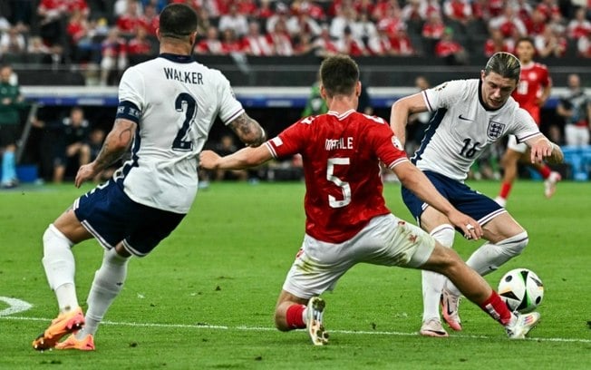 Os ingleses Kyle Walker (esq.) e Connor Gallagher (dir.) e o dinamarquês Joakim Maehle (centro) disputam a bola durante a partida da fase de grupos da Euro 2024, no dia 20 de junho de 2024, em Frankfurt.