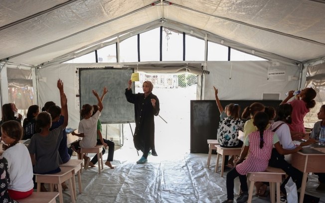 Crianças palestinas assistem a uma aula em escola temporária supervisionada pelo Unicef em Khan Yunis, sul da Faixa de Gaza, em 19 de setembro de 2024