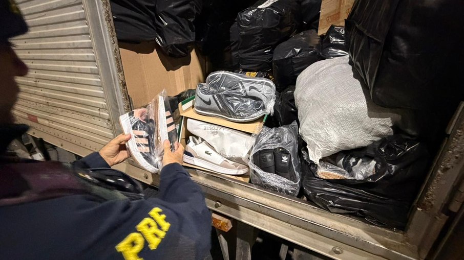 Agente da PRF inspeciona tênis falsificados apreendidos em caminhão na BR-459, em Lorena (SP); carga seguia para Aparecida sem nota fiscal Agente da PRF inspeciona tênis falsificados apreendidos em caminhão na BR-459, em Lorena (SP); carga seguia para Aparecida sem nota fiscal
