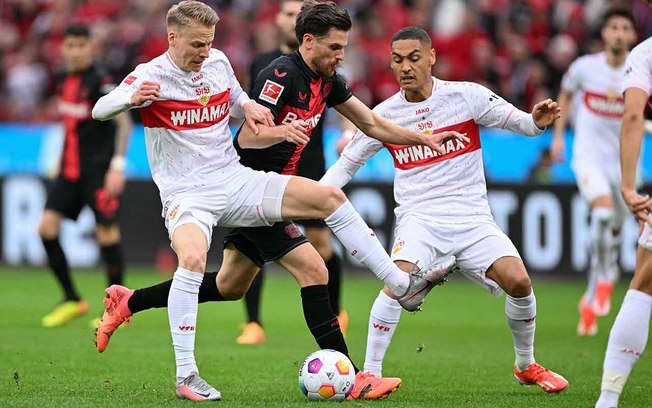 Hoffman, do Leverkusen ( de preto) tenta passar pela marcação dupla de Führich e Enzo Millot, do Stuttgart