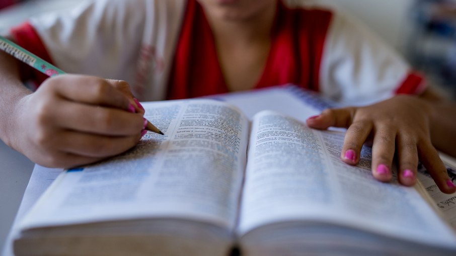 Aluna estuda com livro em sala de aula