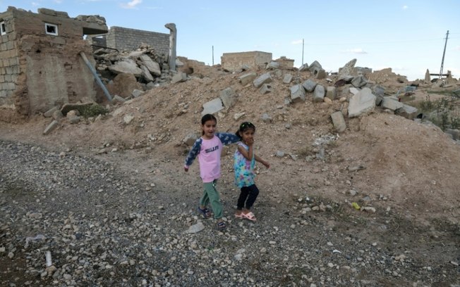 Crianças da etnia yzidi caminham entre ruínas na aldeia de Solagh, na região iraquiana de Sinjar Crianças da etnia yzidi caminham entre ruínas na aldeia de Solagh, na região iraquiana de Sinjar
