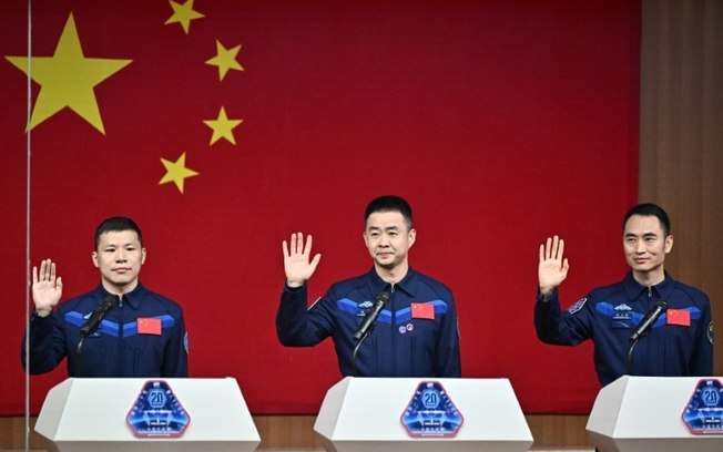 A tripulação da missão Shenzhou-20 (da esquerda para a direita, Wang Jie, Chen Dong e Chen Zhongrui) acena durante uma coletiva de imprensa no Centro de Lançamento Espacial de Jiuquan, no noroeste da China, em 23 de abril de 2025