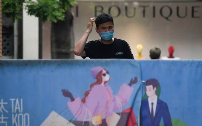 Homem caminha por uma rua em Pequim usando máscara