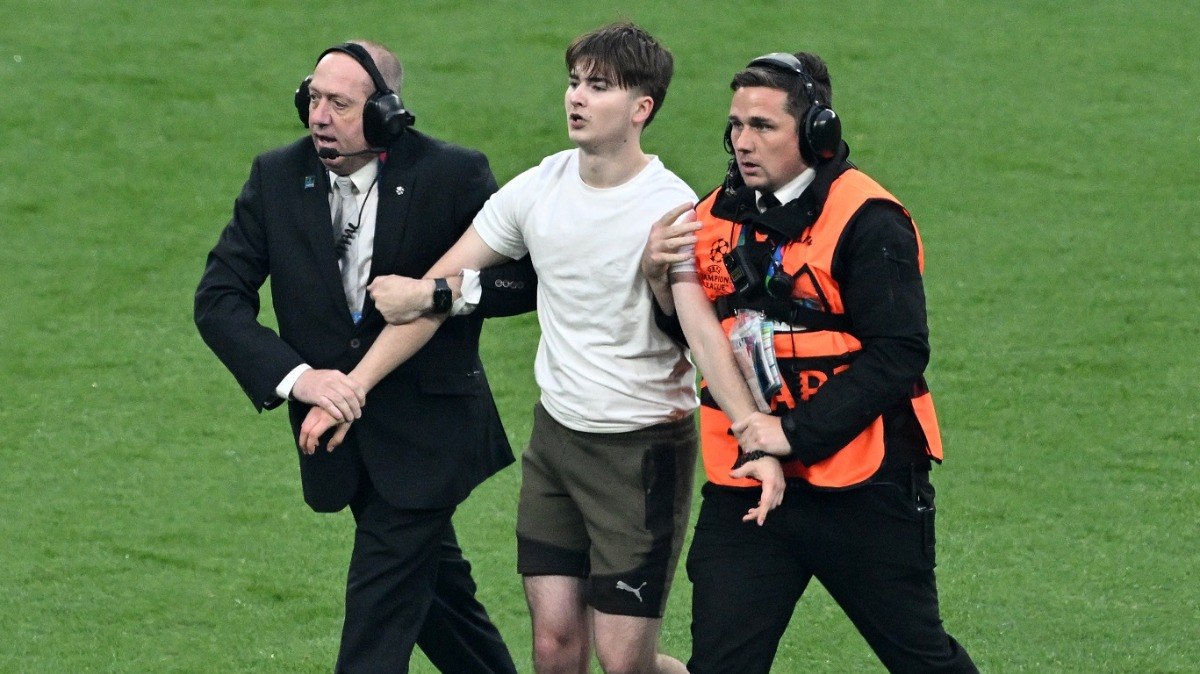 Um invasor de campo é abordado por comissários durante a final da Liga dos Campeões da UEFA entre Borussia Dortmund e Real Madrid, no estádio de Wembley, em Londres, em 1º de junho de 2024. 