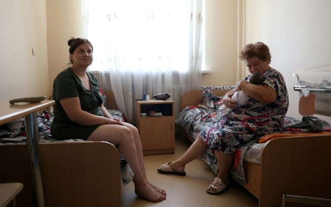 Tetyana (à direita) segura seu neto Timofiy, nascido dois dias antes, em frente à sua filha Tetyana Pishchuk, de 31 anos, na enfermaria do centro neonatal em Pokrovsk, região de Donetsk, em 20 de julho de 2024