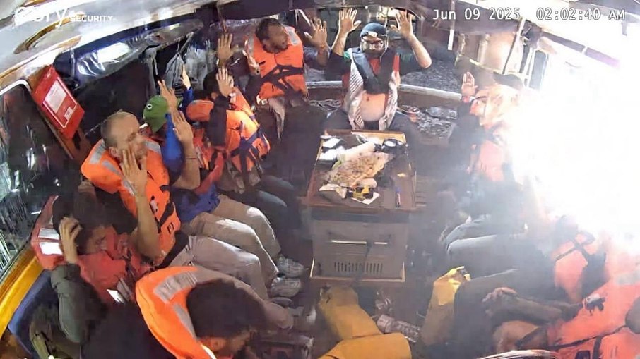Ativistas com as mãos para cima a bordo do Madleen, durante abordagem israelense