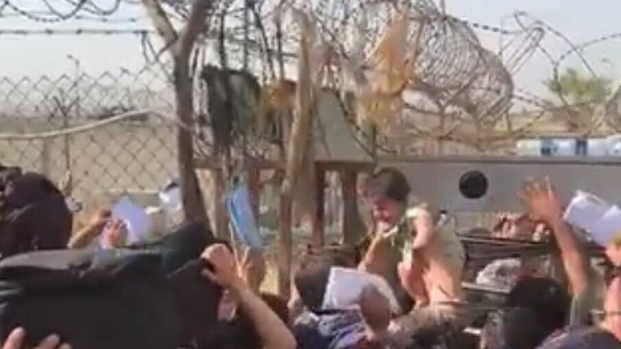 Criança é levada por multidão até atravessar muro do aeroporto de Cabul