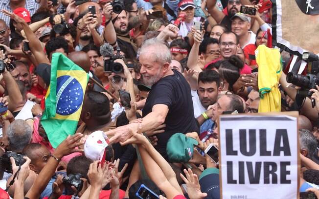 Lula segura bandeira do Brasil enquanto é carregado por apoiadores