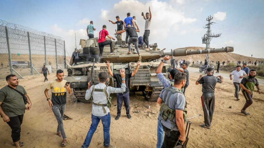 Palestinos assumem o controle de um tanque israelense após cruzar a cerca da fronteira com Israel de Khan Yunis, no sul da Faixa de Gaza, em 7 de outubro de 2023