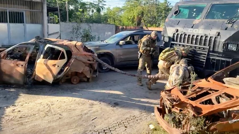 Agentes removem veículos carbonizados usados como barricada no acesso