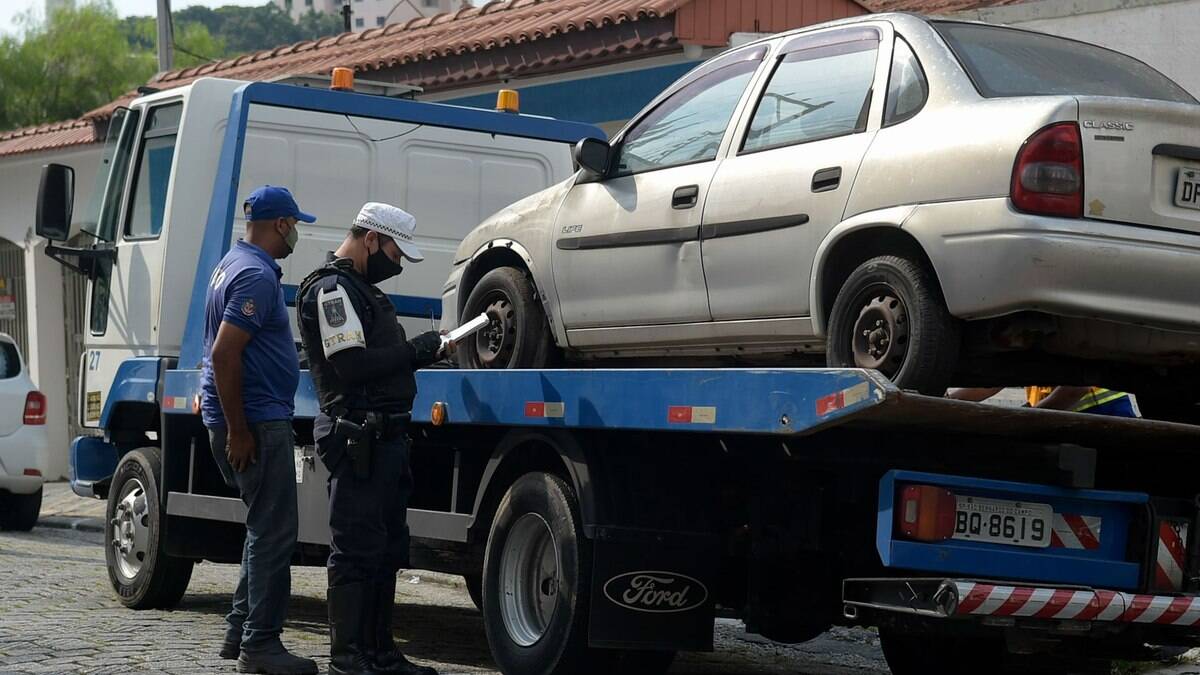 Guardas de trânsito adesivam os veículos que podem ser levados para os pátios da cidade.