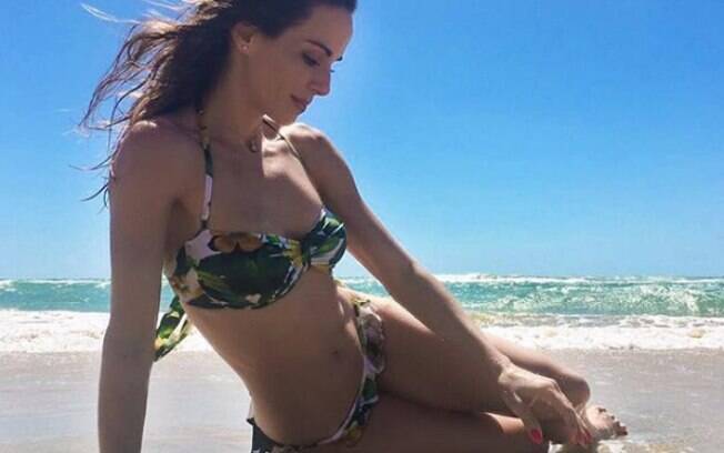 Ana Furtado posando sensual, na praia e de biquíni. Paisagem é destaque também