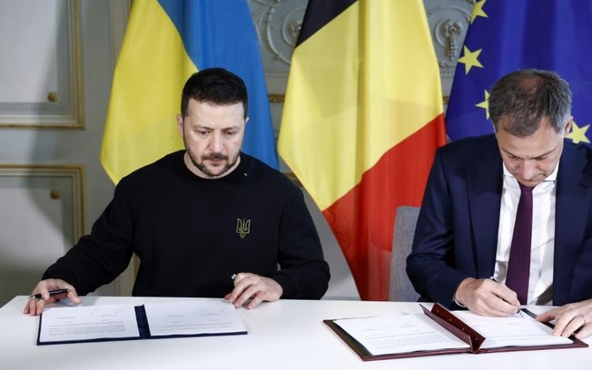 O presidente ucraniano Volodimir Zelensky (à esquerda) e o primeiro-ministro belga, Alexander de Croo, assinam o acordo de segurança bilateral em 28 de maio de 2024 em Bruxelas